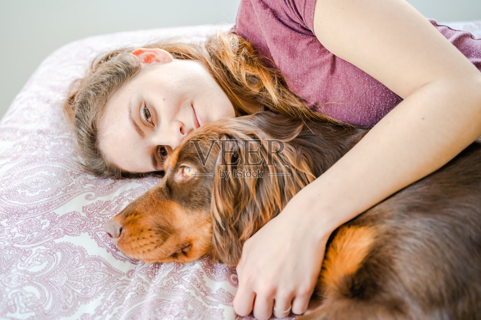 一个白人女孩躺在床上抱着她的狗。马略卡岛，西班牙照片摄影图片