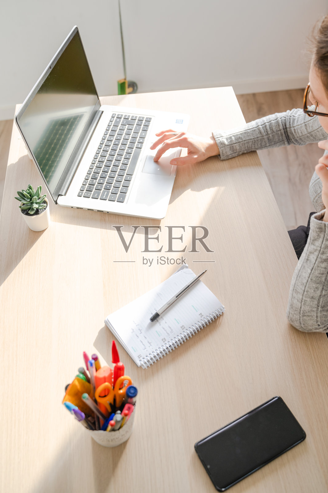 在西班牙马略卡岛帕尔马的办公室里，一个白人女孩在她的桌子上用笔记本电脑工作。照片摄影图片