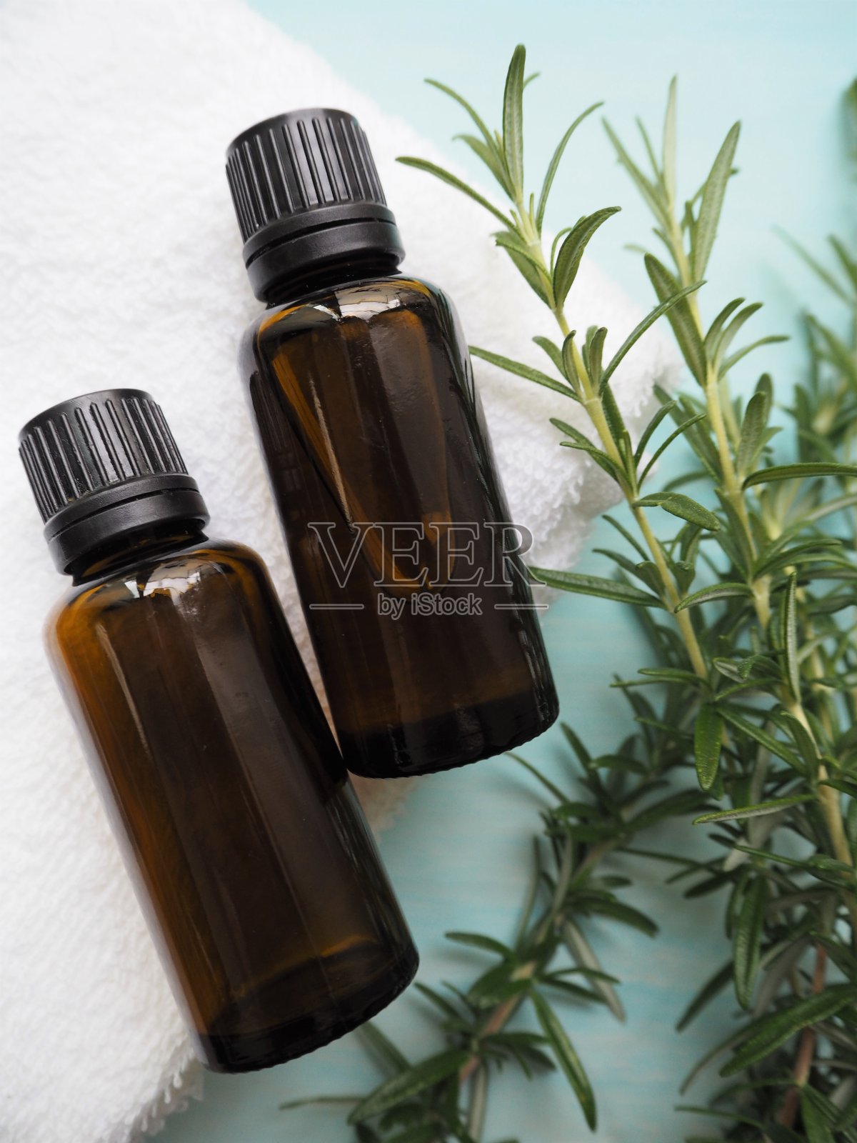 两个精油瓶和新鲜迷迭香叶。芳香疗法的形象。照片摄影图片