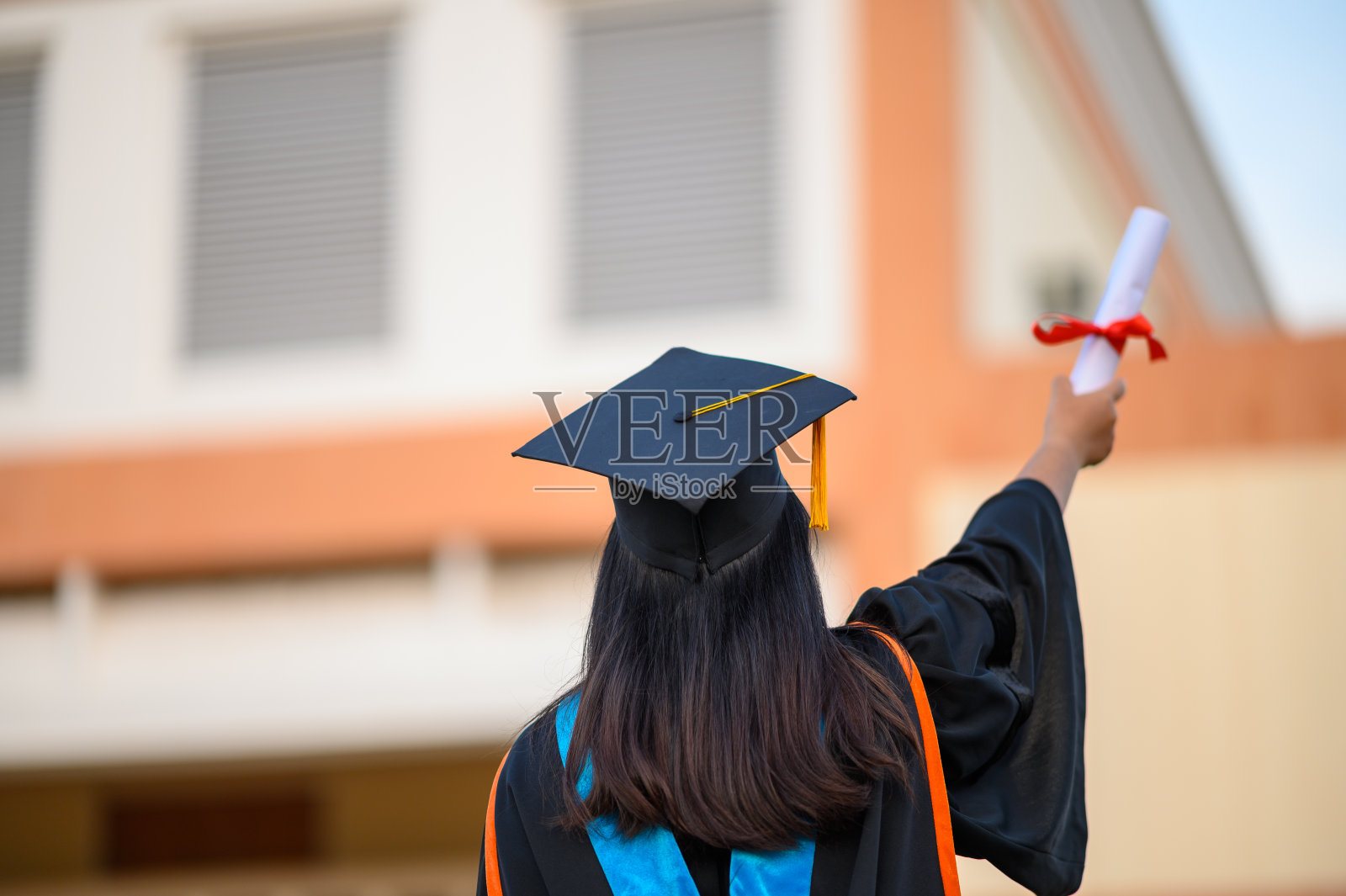 毕业生戴着黑帽子拿着大学毕业证书，向概念教育祝贺。毕业典礼，祝贺大学毕业生。照片摄影图片