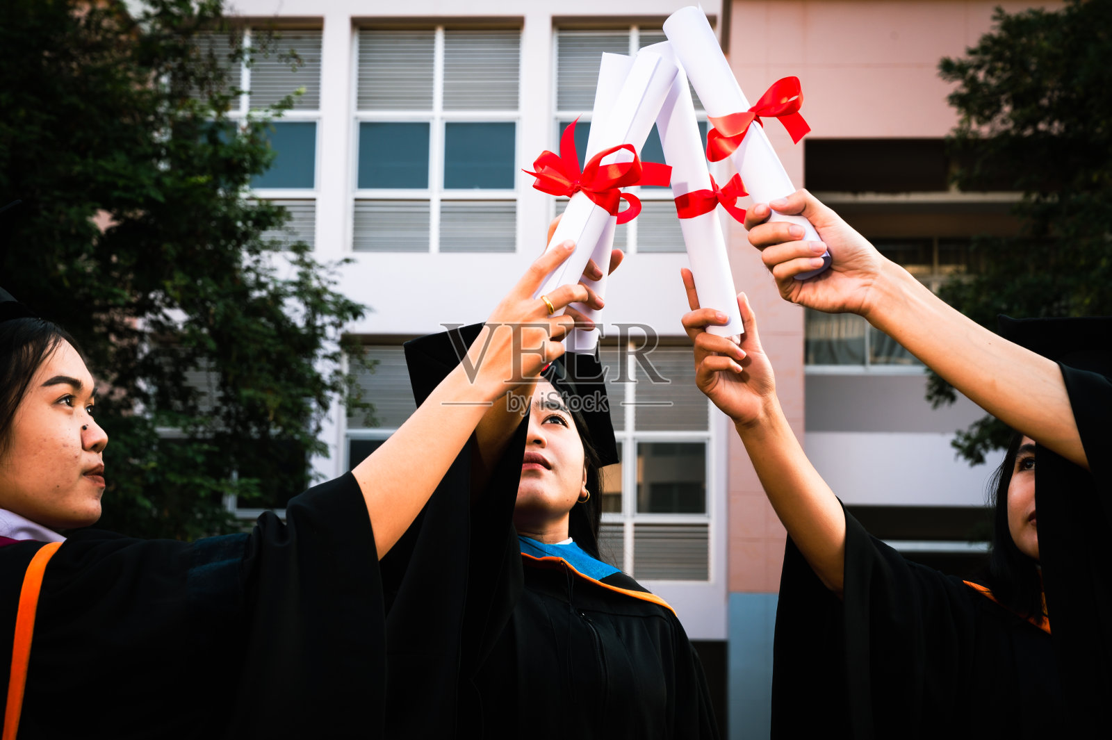 毕业生戴着黑帽子拿着大学毕业证书，向概念教育祝贺。毕业典礼，祝贺大学毕业生。照片摄影图片