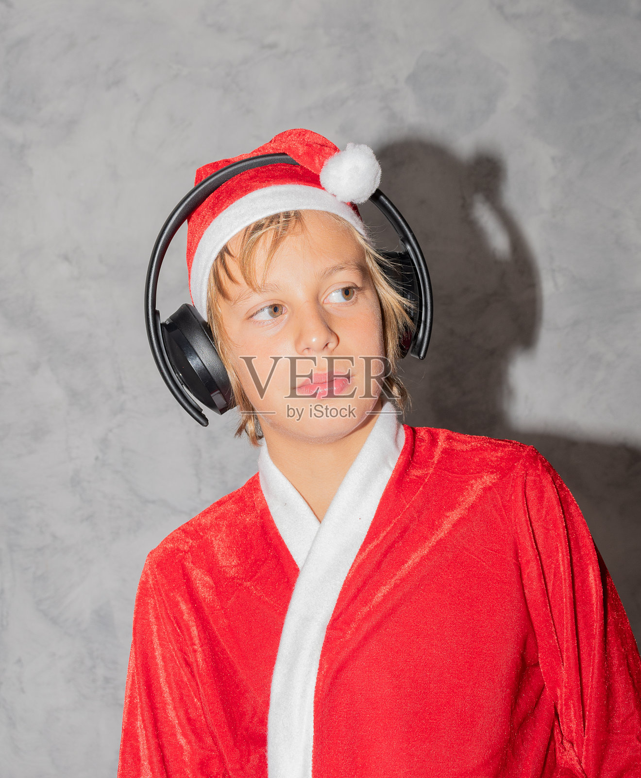 在灰色的背景下，男孩打扮成圣诞老人照片摄影图片