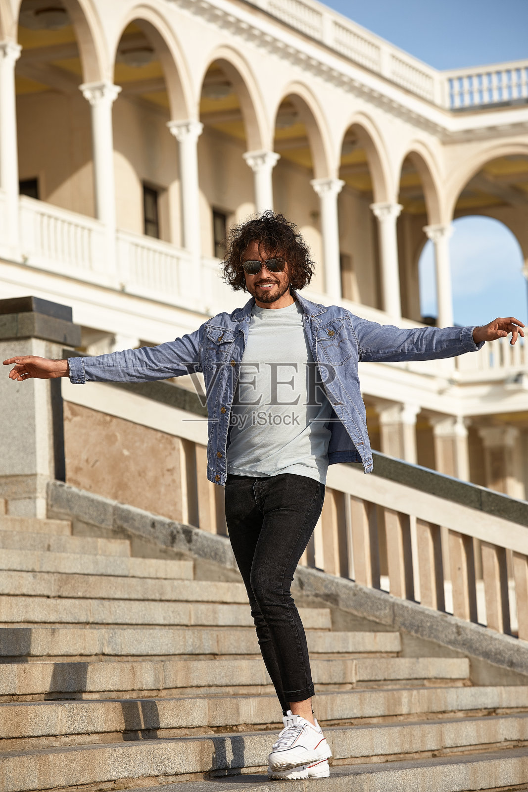 一个时髦的家伙，背景是玻璃石墙，目光移开。强壮而严格的男性。在休闲服装照片摄影图片