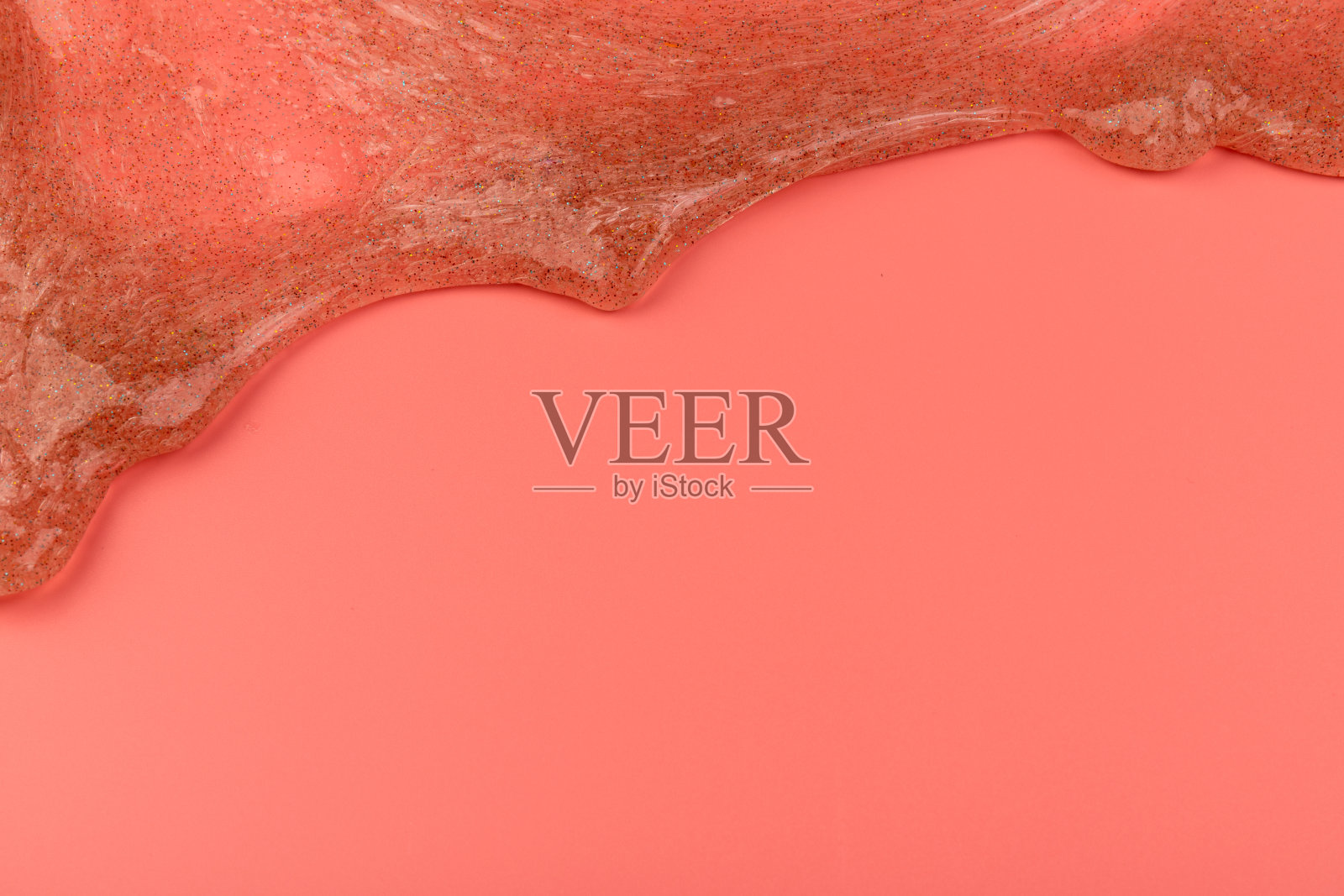 珊瑚透明黏液与气泡内部粉红色的背景。孩子们的玩具黏液。照片摄影图片