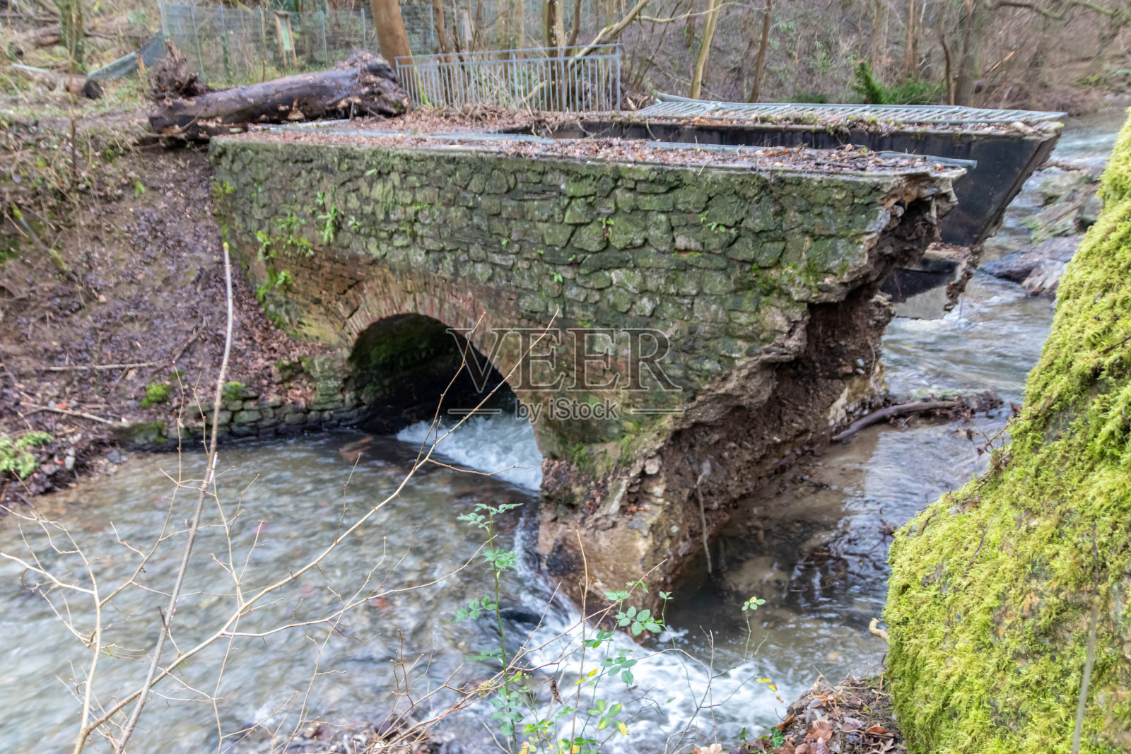 大雨过后，洪水冲毁了河湾的一座桥，洪水显示了大自然的力量，以及对危险天气、风暴、旋风、龙卷风和飓风进行保险的必要性照片摄影图片