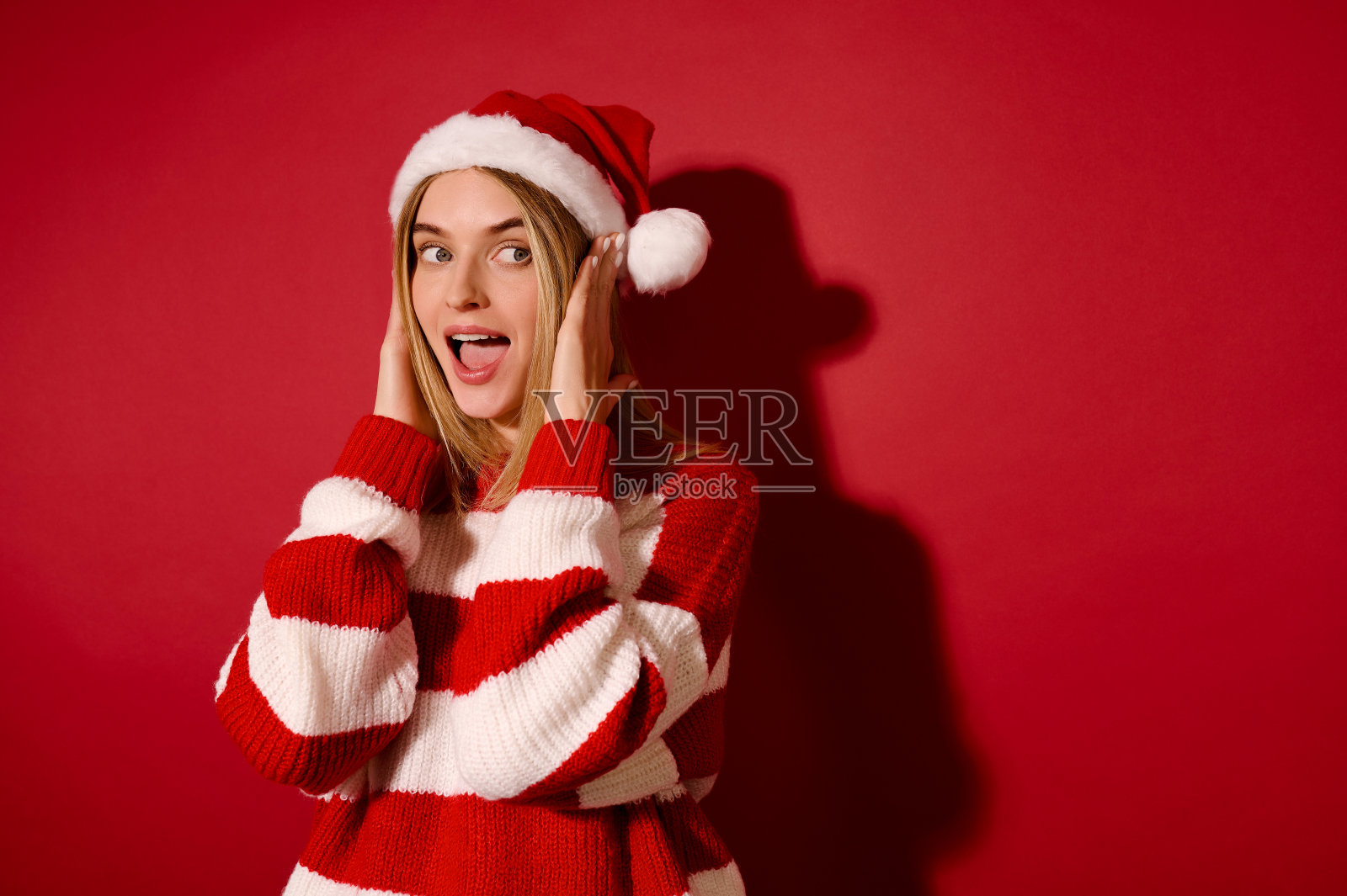 年轻漂亮的女孩，戴着圣诞帽，穿着条纹毛衣照片摄影图片
