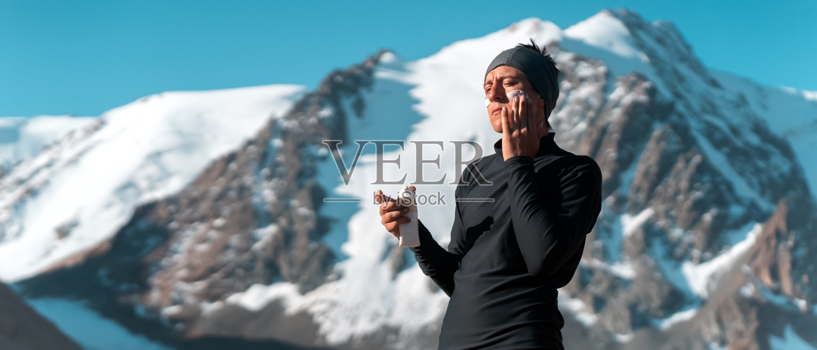 旅行者把防晒霜涂在脸上。照片摄影图片