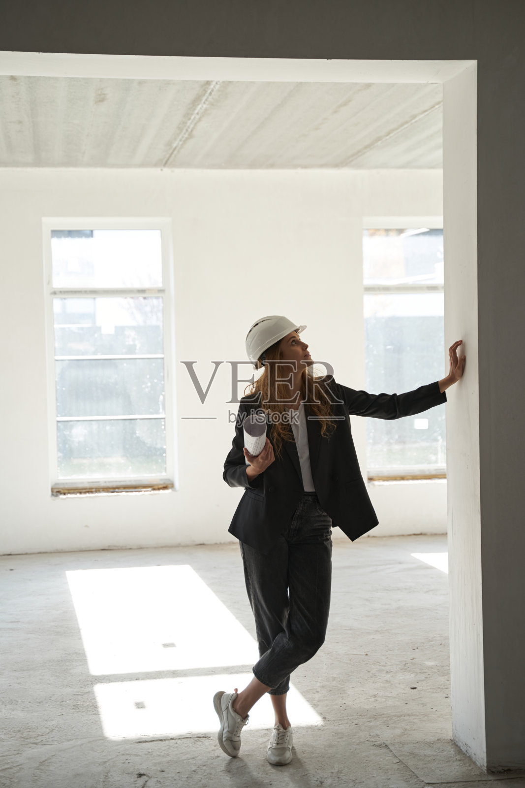 一个女人拿着设计图站在房间里看着墙照片摄影图片