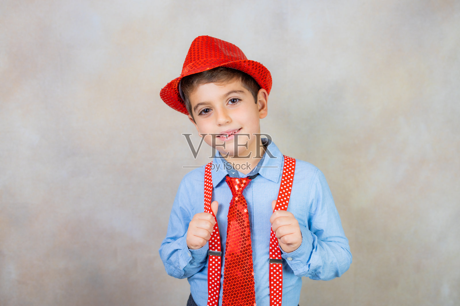 狂欢节上戴着帽子、背带和领带的滑稽男孩照片摄影图片