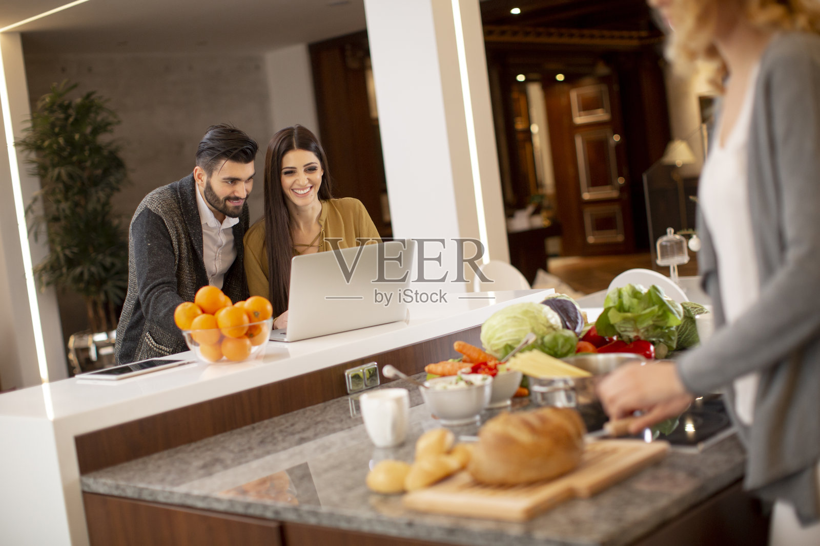 一群年轻人准备饭菜，在笔记本电脑上寻找食谱，玩得很开心照片摄影图片