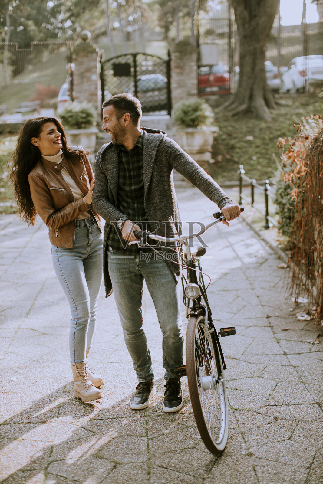 年轻夫妇骑着自行车在秋天的公园散步照片摄影图片