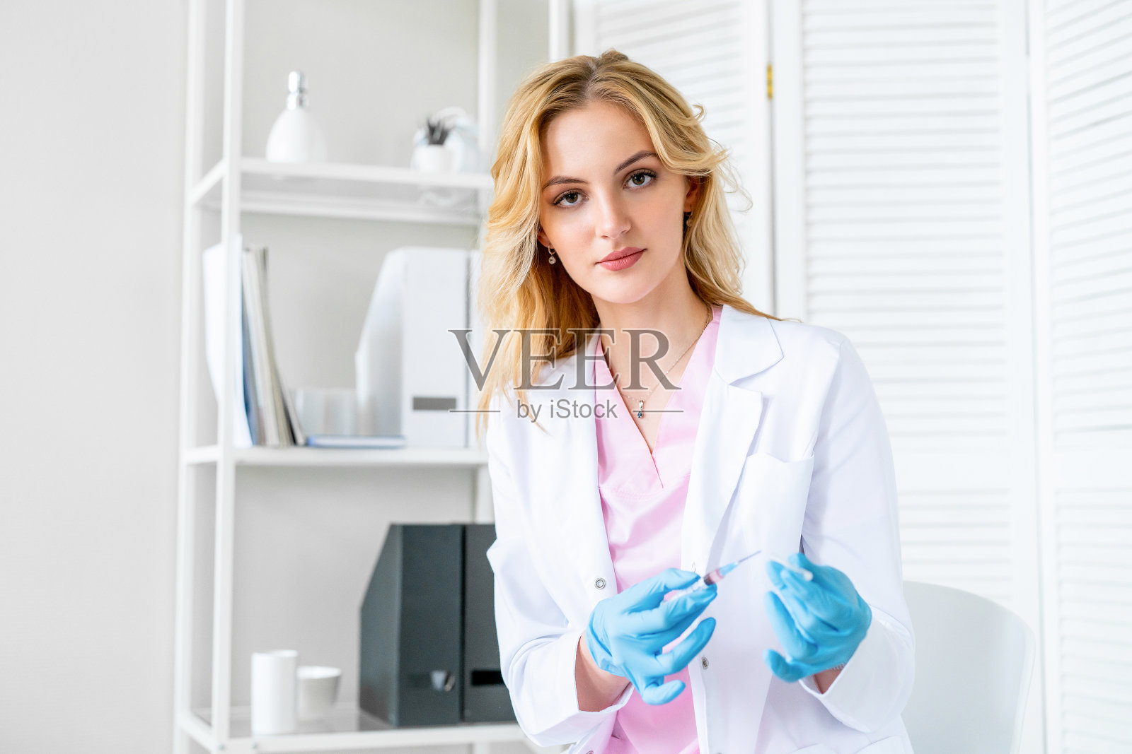 穿着白大褂，手里拿着疫苗的快乐护士的肖像。为人口接种covid - 19疫苗。全球大流行。照片摄影图片