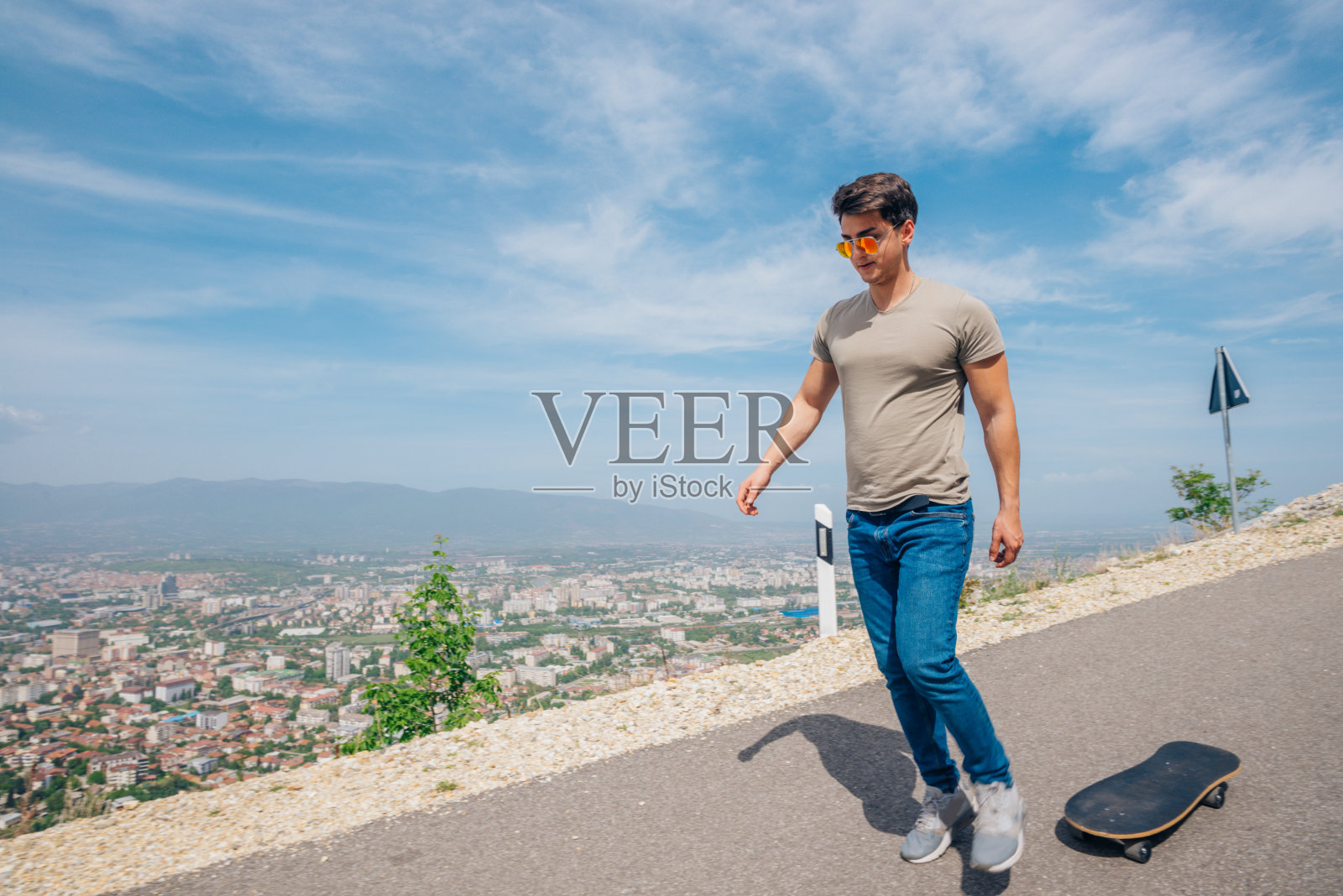 都市酷滑板者准备下坡滑行，在他的长板上做一些特技和诡计，在骑的时候抓住板。照片摄影图片