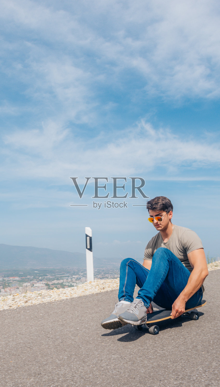 都市酷滑板者准备下坡滑行，在他的长板上做一些特技和诡计，在骑的时候抓住板。照片摄影图片