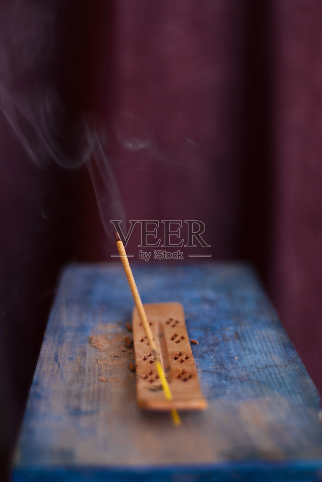 熏香用烟线点燃，背景为深色，底色为天蓝色照片摄影图片