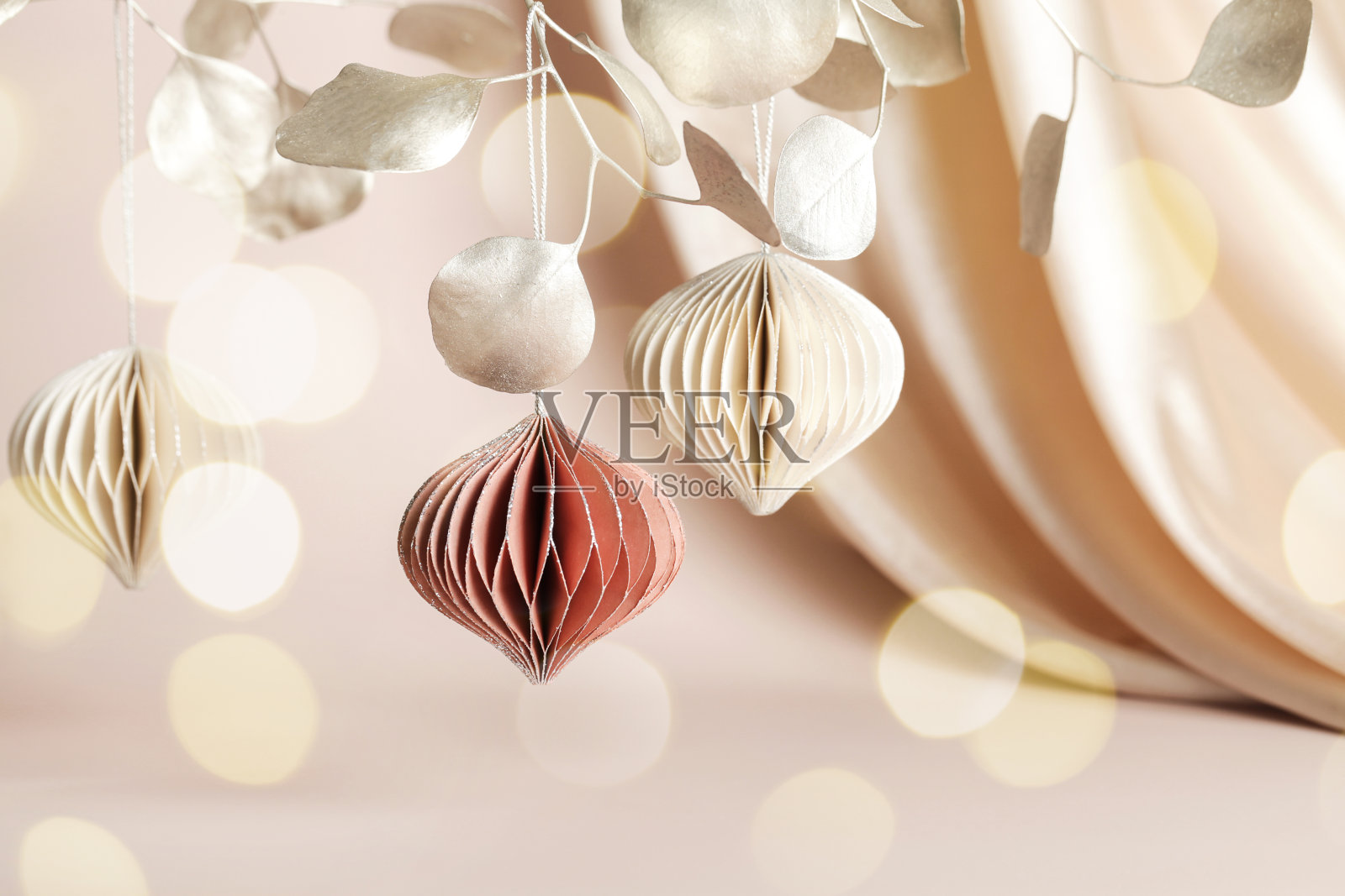 圣诞蜂巢纸装饰在金色的树枝上米色的背景与纺织品和散景。节日、贺卡、环保节日。照片摄影图片