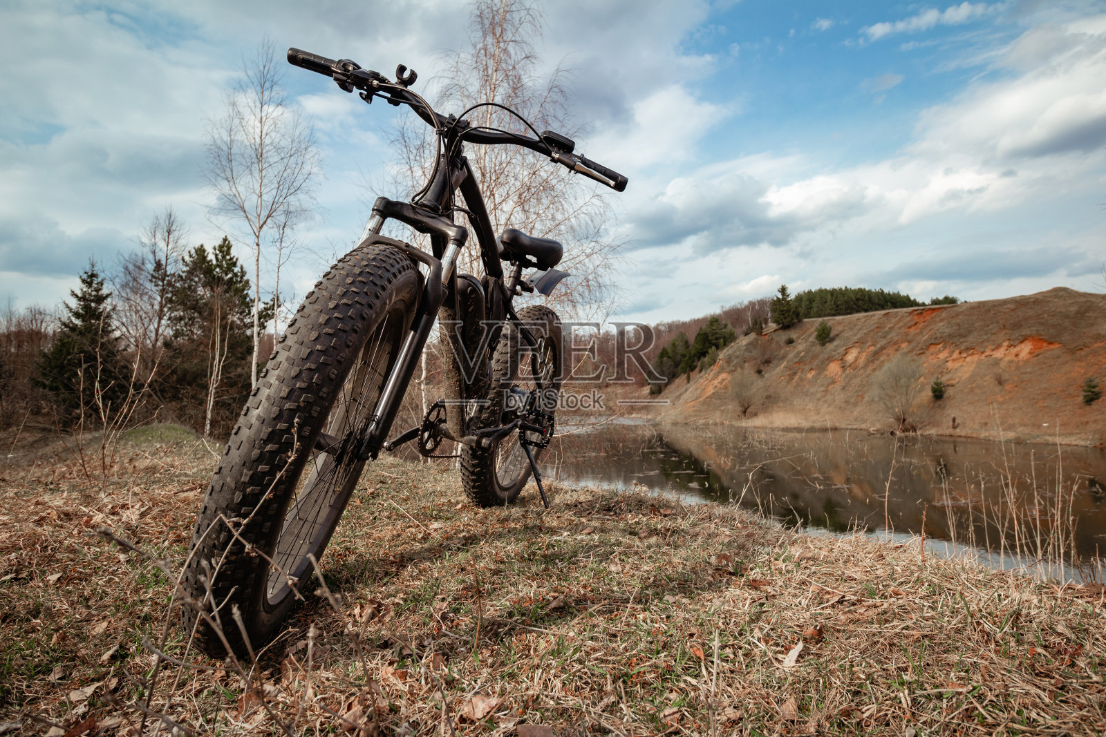 一辆黑色的大自行车停在乡村的湖边。一个非常健康的爱好。照片摄影图片