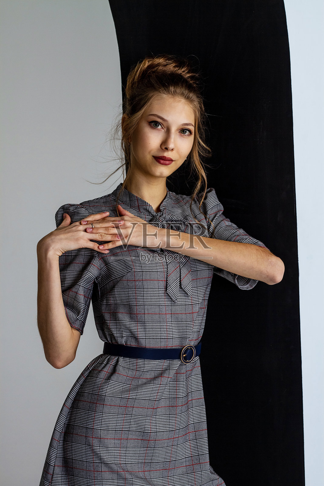 美丽的年轻女孩穿着一件灰色的严格的连衣裙，头发盘成一个发髻，是一个年轻女孩的肖像照片摄影图片