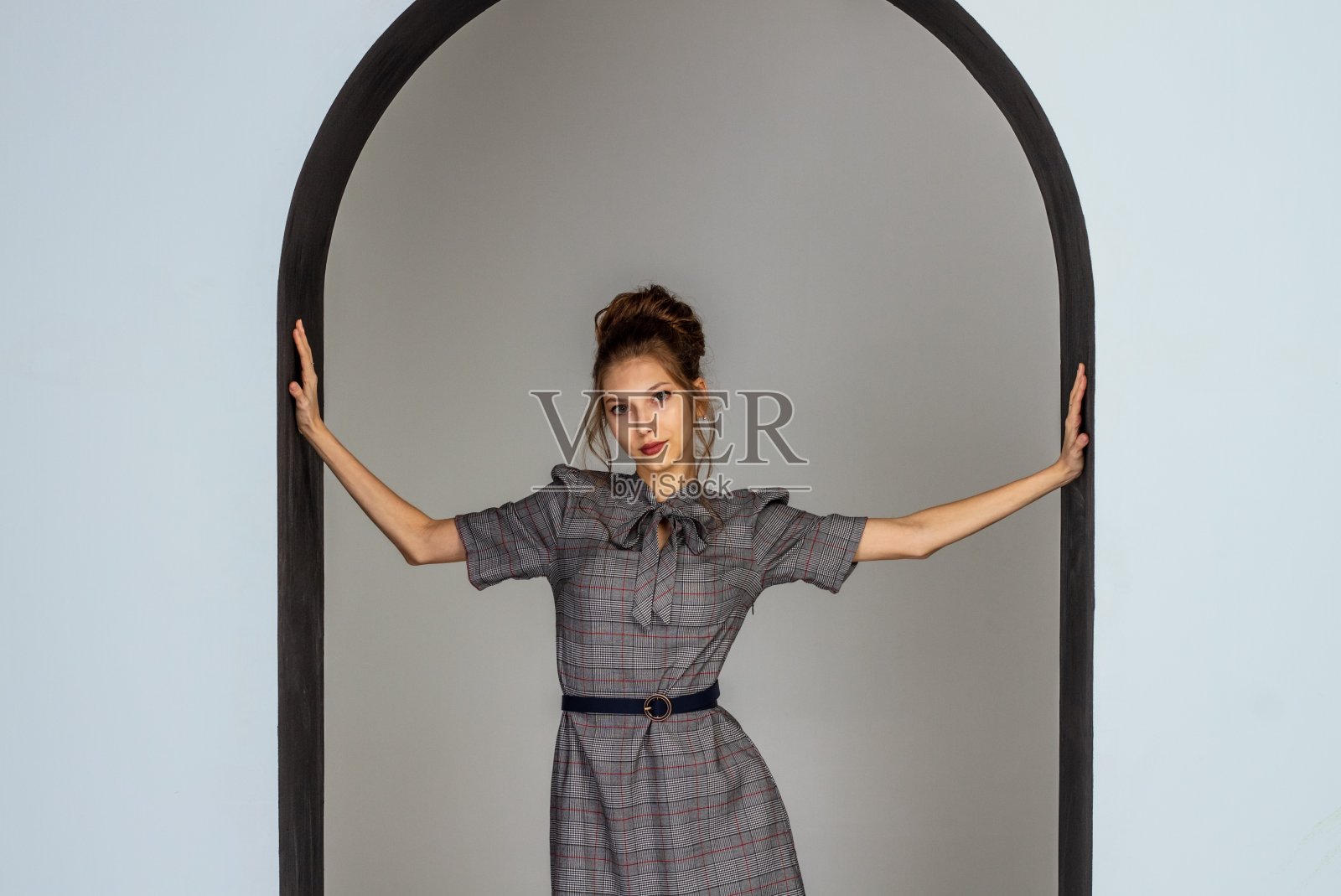 美丽的年轻女孩穿着一件灰色的严格的连衣裙，头发盘成一个发髻，是一个年轻女孩的肖像照片摄影图片