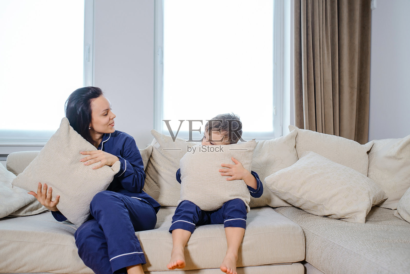 快乐的年轻母亲躺在床上和她的儿子玩得很开心照片摄影图片