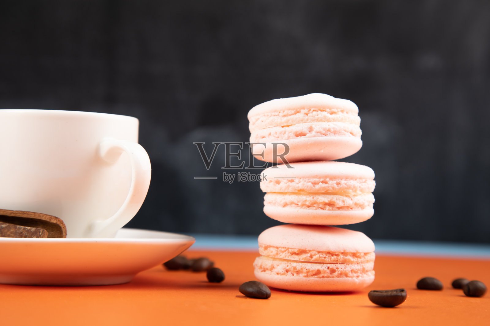 白色马卡龙和咖啡，橘色背景，肉桂。咖啡种子照片摄影图片