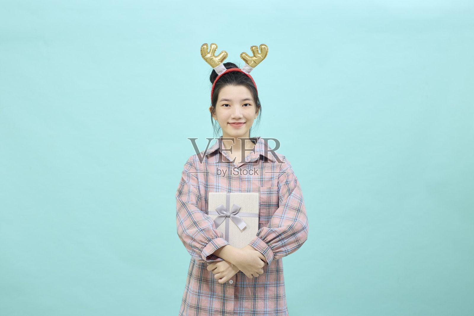 肖像美丽的女孩拿着蓝色背景的礼品盒。圣诞新年销售欢乐理念照片摄影图片