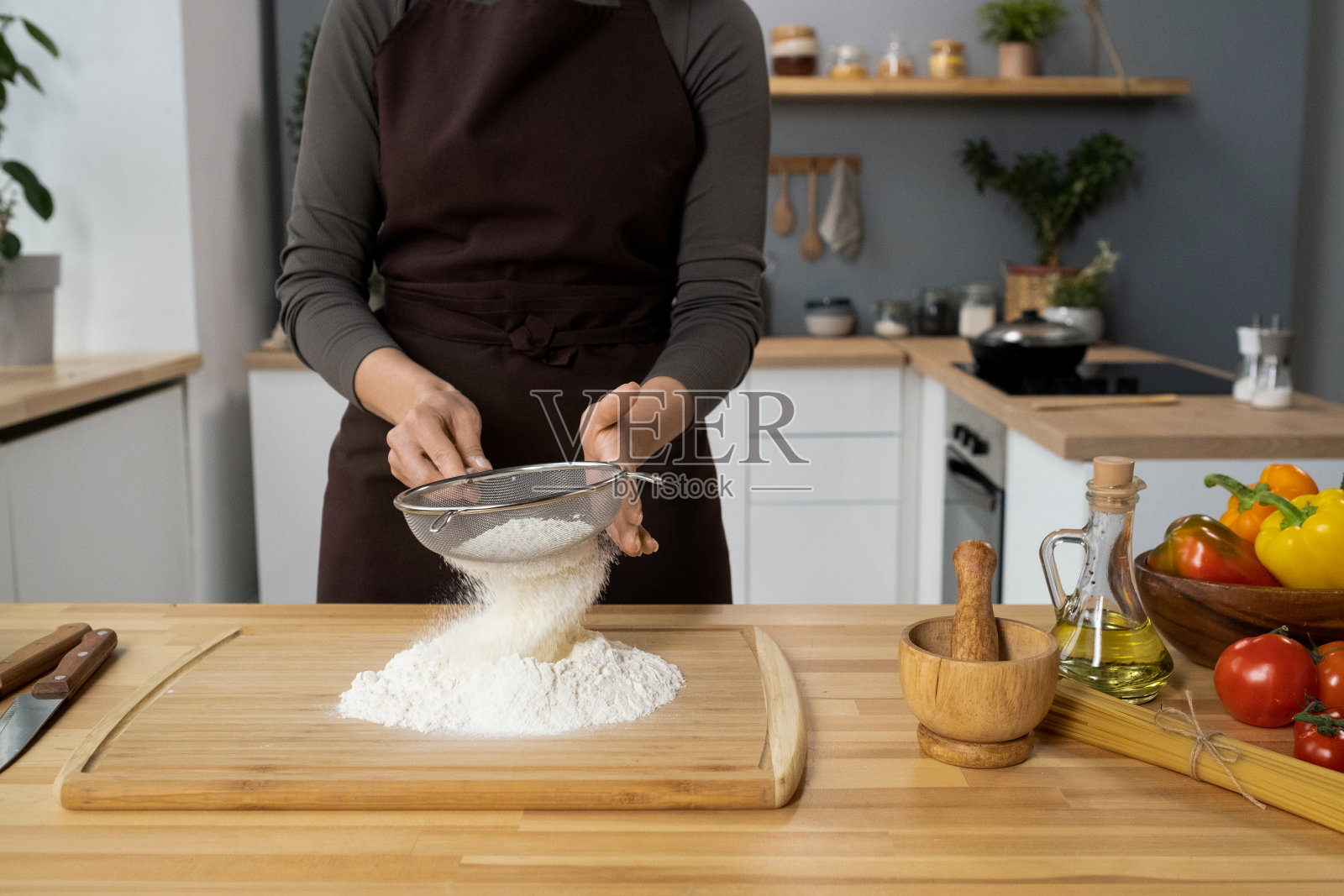 穿着围裙的年轻女性正在用木板筛面粉照片摄影图片