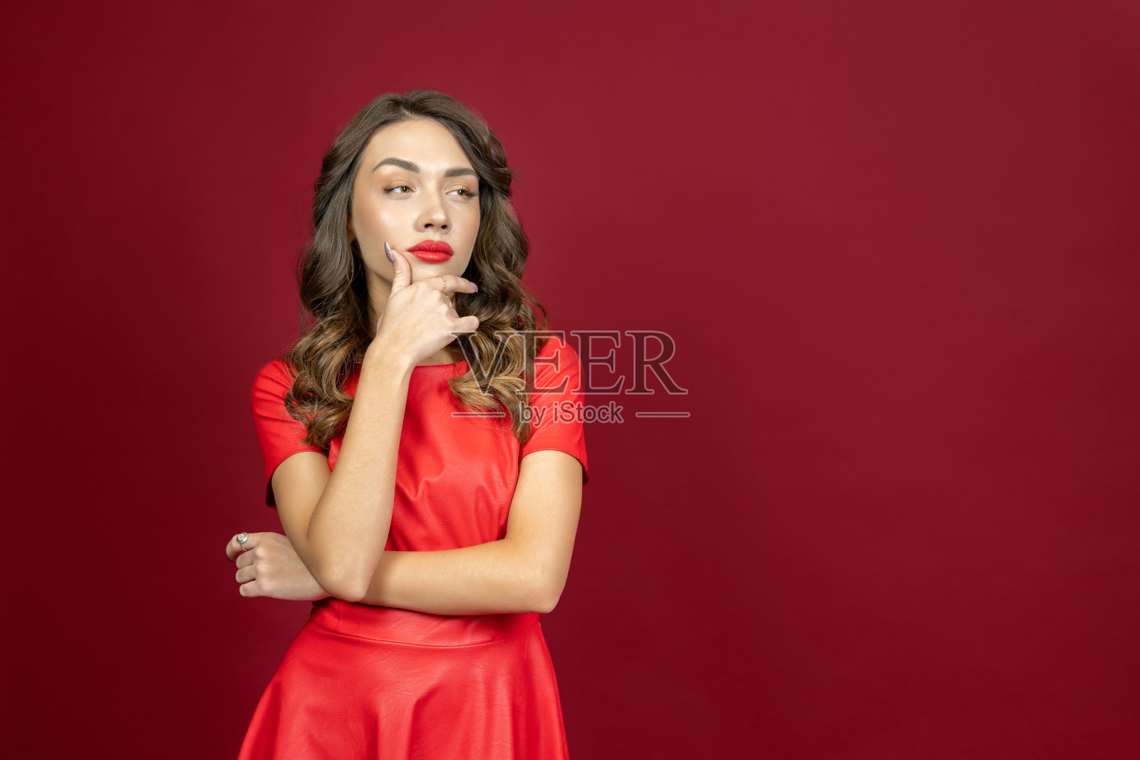 在红色背景下，女人看起来若有所思照片摄影图片