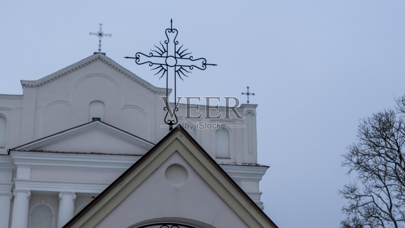 教堂入口大门上天主教十字架的特写。敬拜和信仰上帝的概念。照片摄影图片