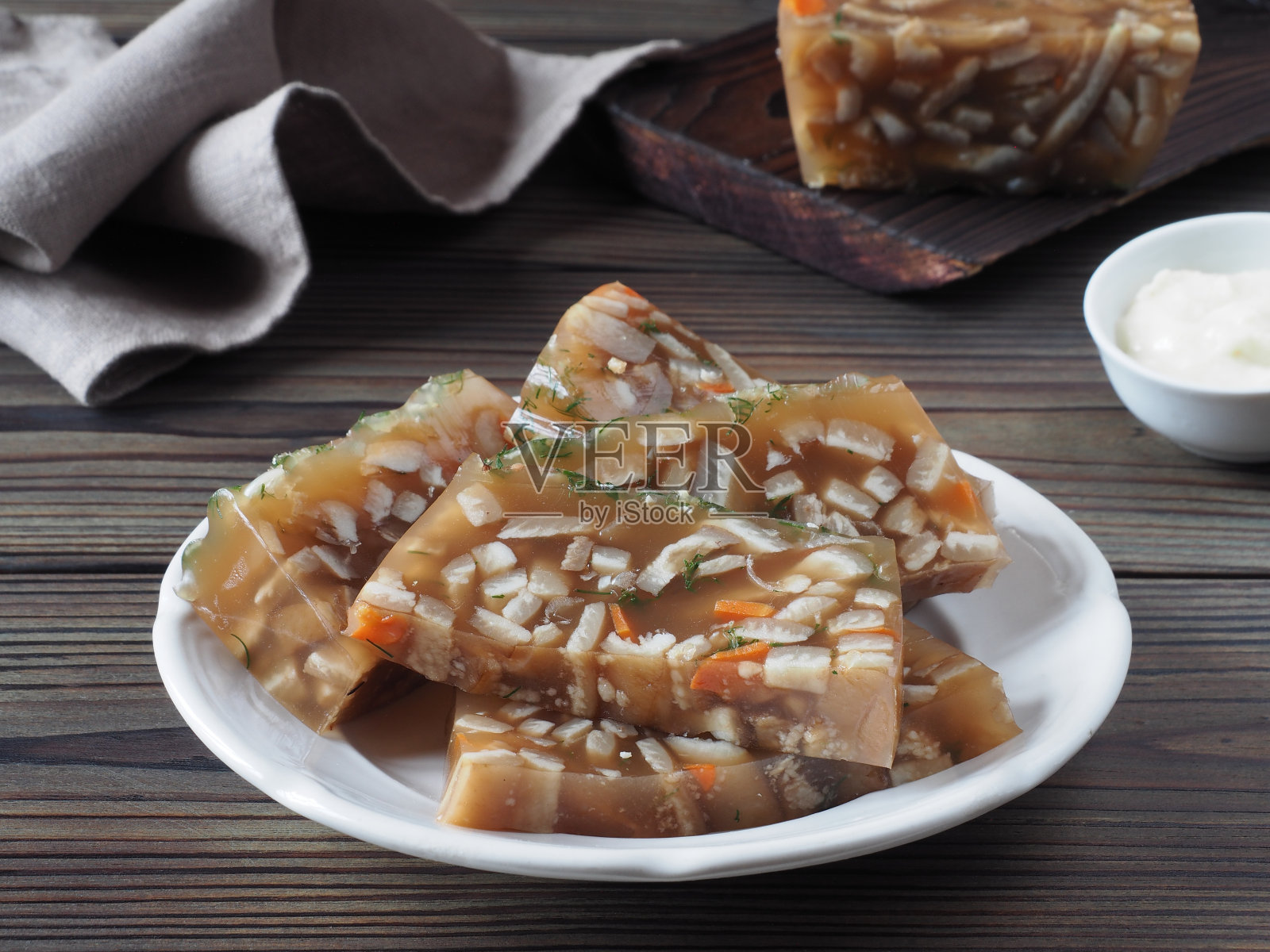 肉冻配猪肉皮，蔬菜和香草放在盘子里，辣根酱，餐巾放在深色的木桌上，平面布局，特写镜头。传统的天然肉汤小吃照片摄影图片