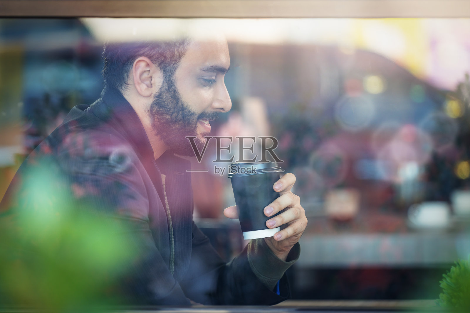 商人微笑着坐在咖啡店的窗口，手里拿着咖啡杯照片摄影图片