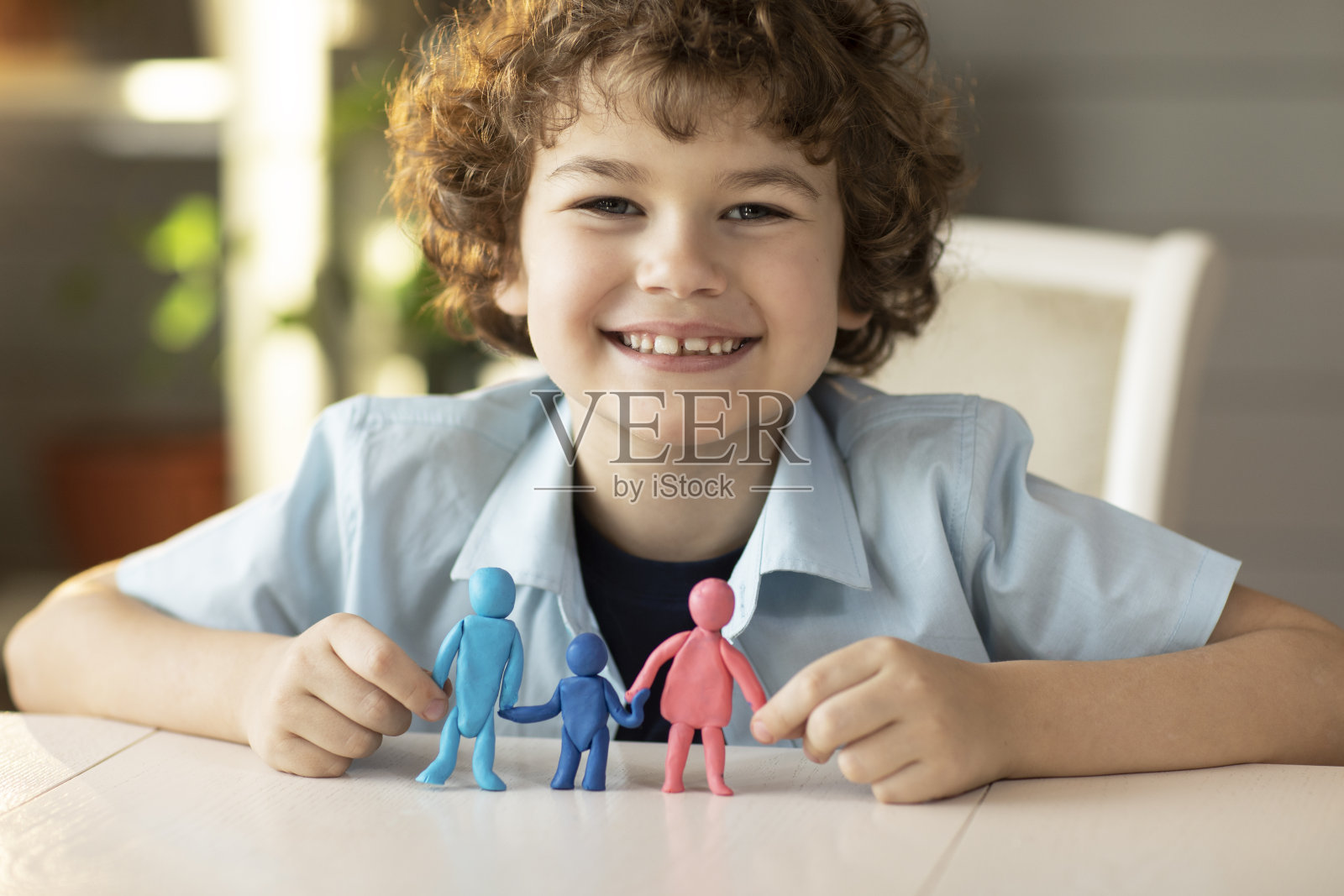 男孩用橡皮泥制作了爸爸、妈妈和孩子的人物形象，镜头前的快乐微笑，家庭关系的概念照片摄影图片