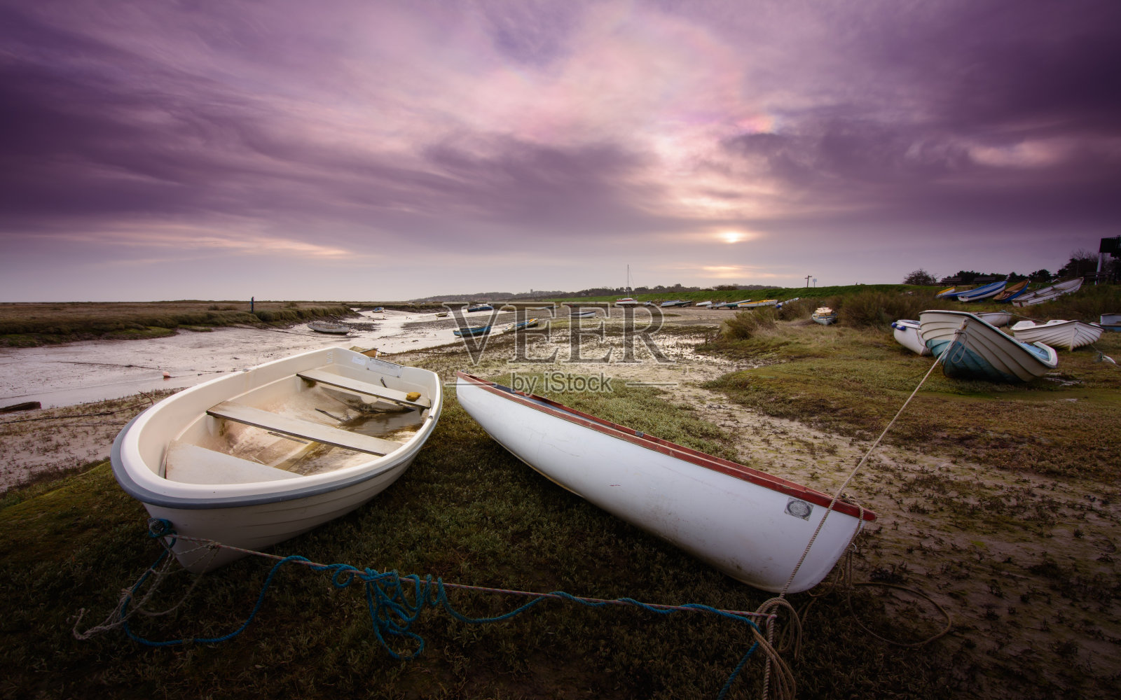 在泥泞的岸边划着小船，在珍珠色的黎明云中照片摄影图片