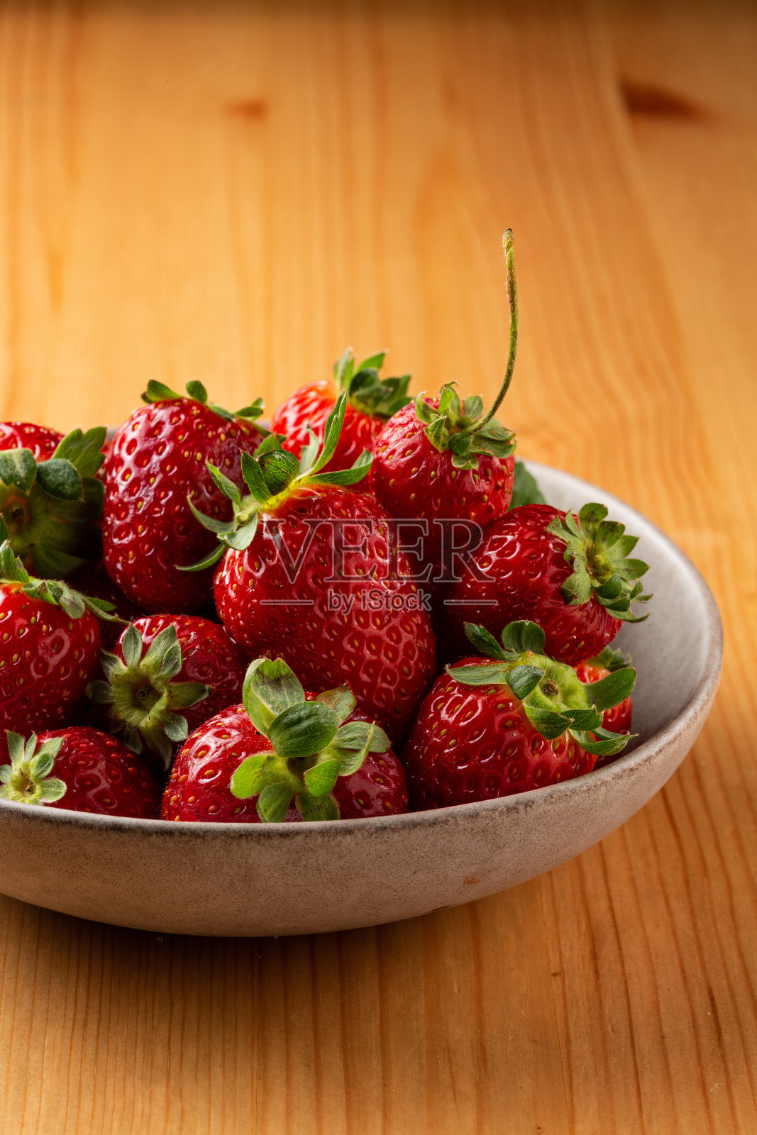 草莓放在木桌上的碗里照片摄影图片