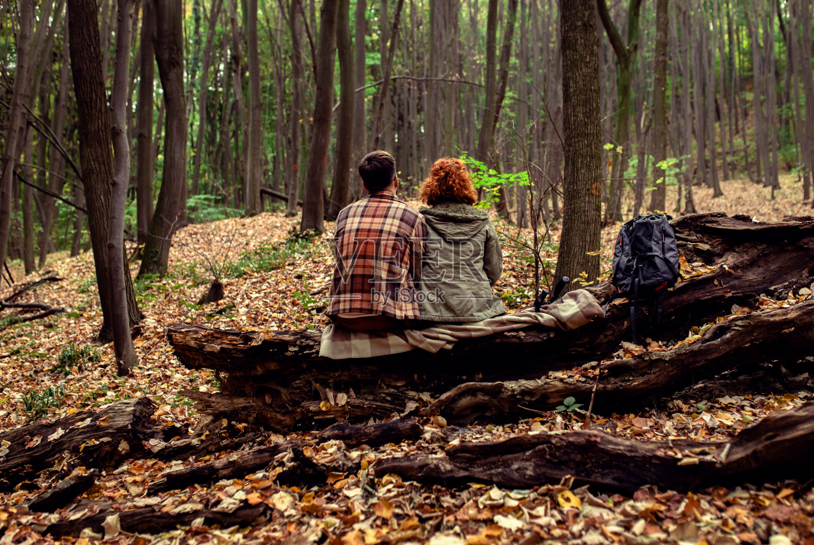 年轻夫妇徒步旅行后坐在森林里的后视镜。照片摄影图片