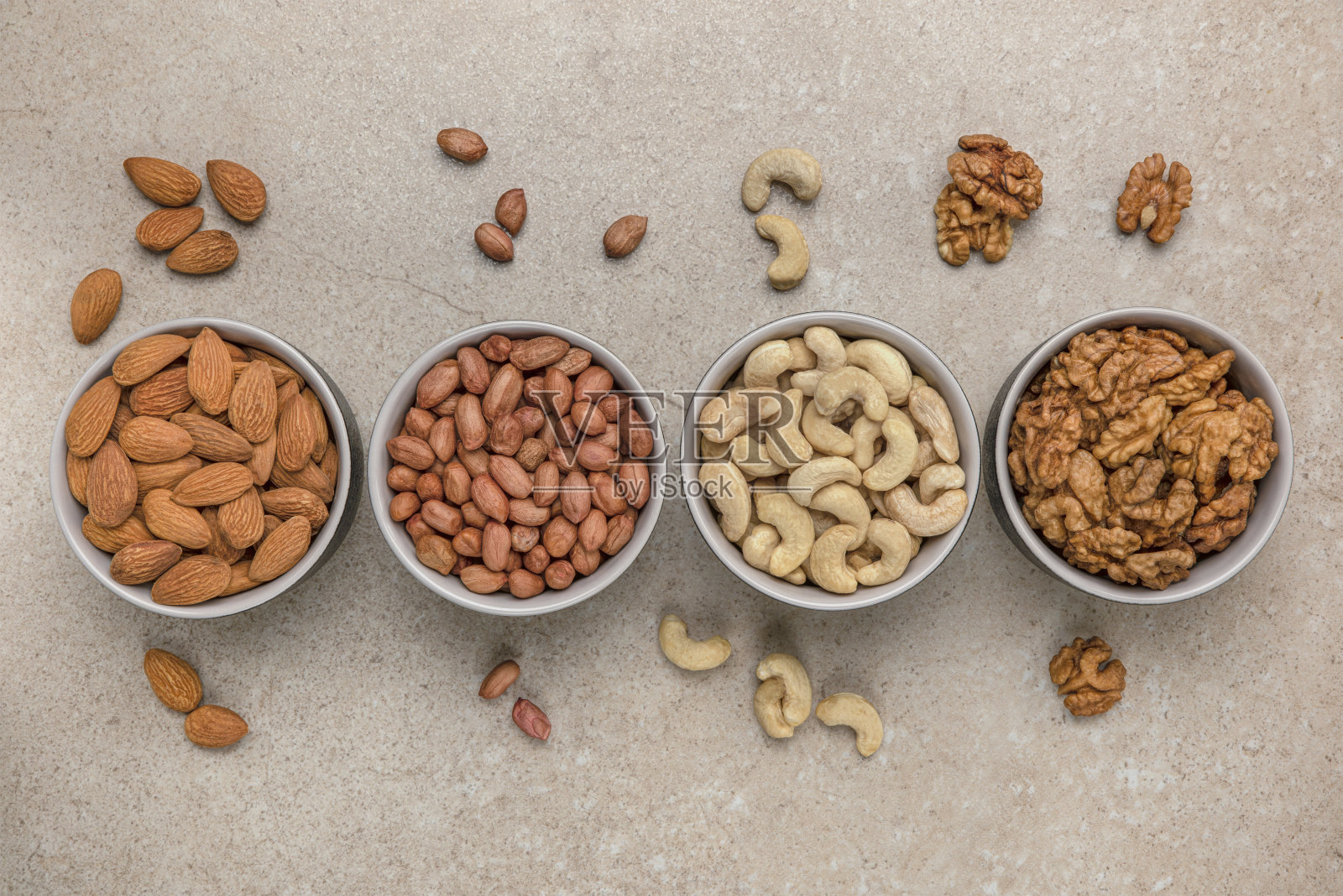 螺母的背景。横幅为大格式印刷，广告和网站设计。不同种类的坚果放在石头台面上的碗里，俯视图。花生，腰果，杏仁，核桃照片摄影图片