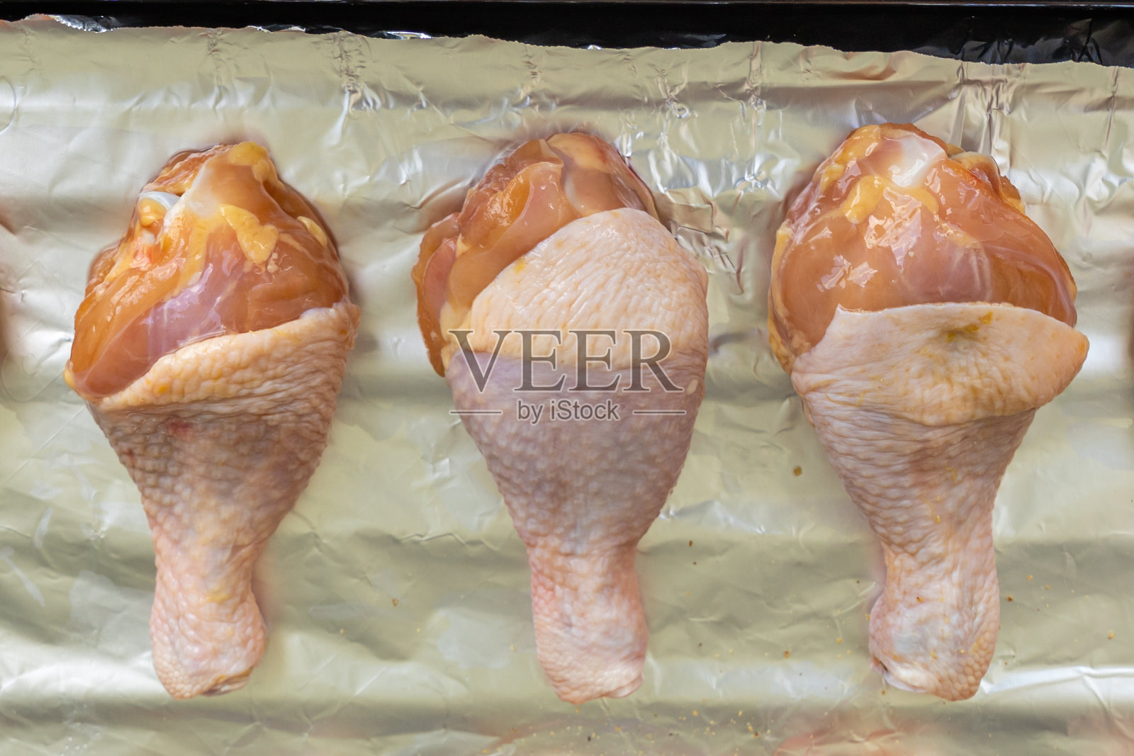新鲜的生鸡腿用铝箔隔开照片摄影图片