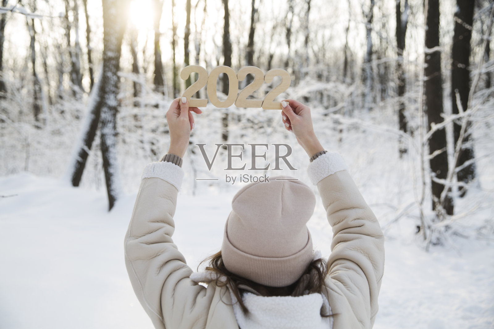 冬天的森林里，女孩手持木制号码“2022”。新年快乐理念照片摄影图片