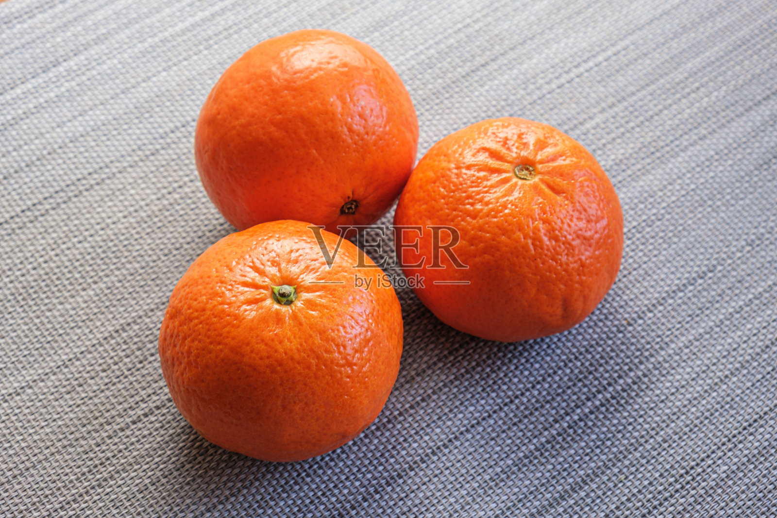 桌子上有三个大橘子。受欢迎的柑橘类水果照片摄影图片