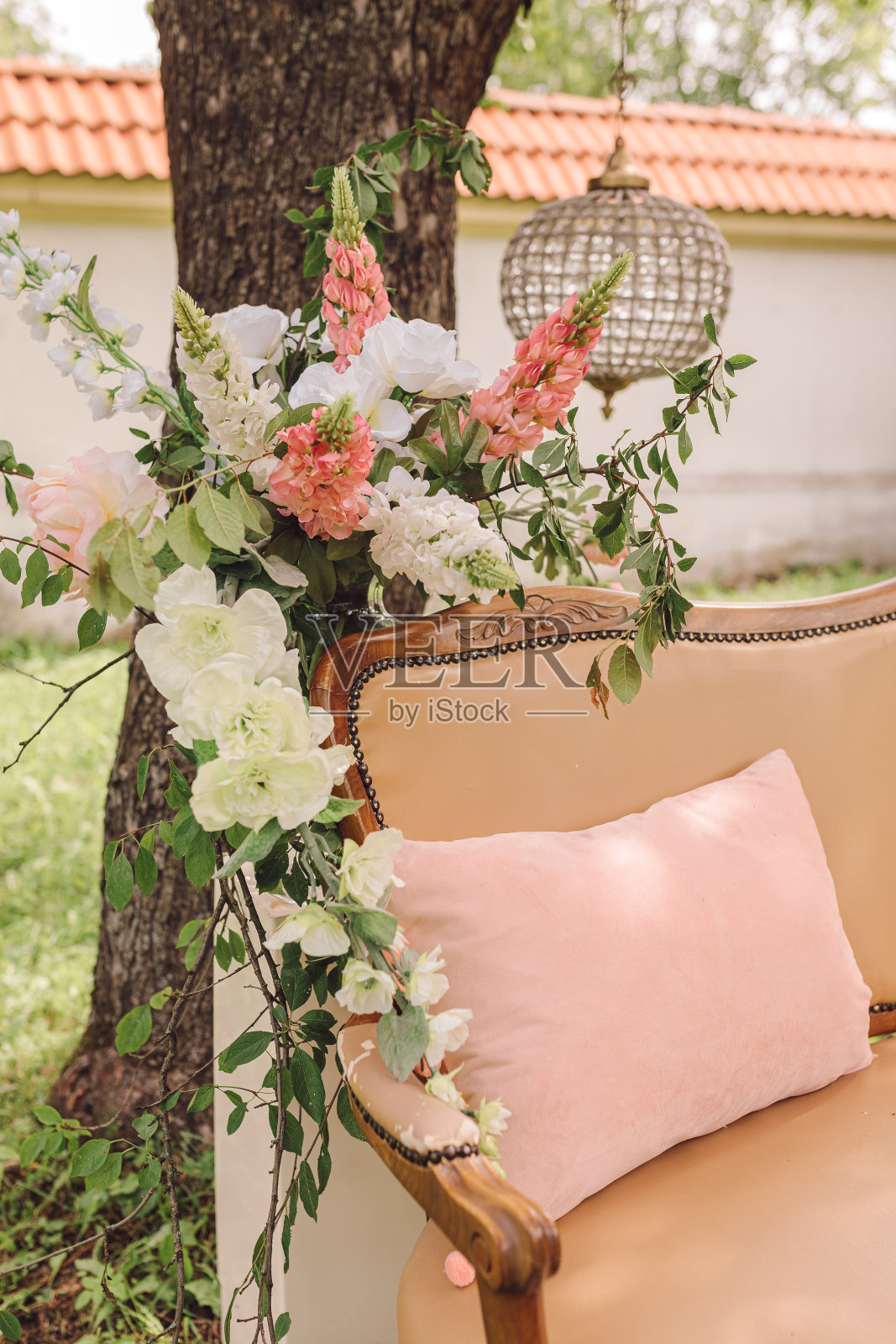 舒适的放松区在树荫下的大树，夏天的凉爽，柳条沙发与靠垫和花照片摄影图片