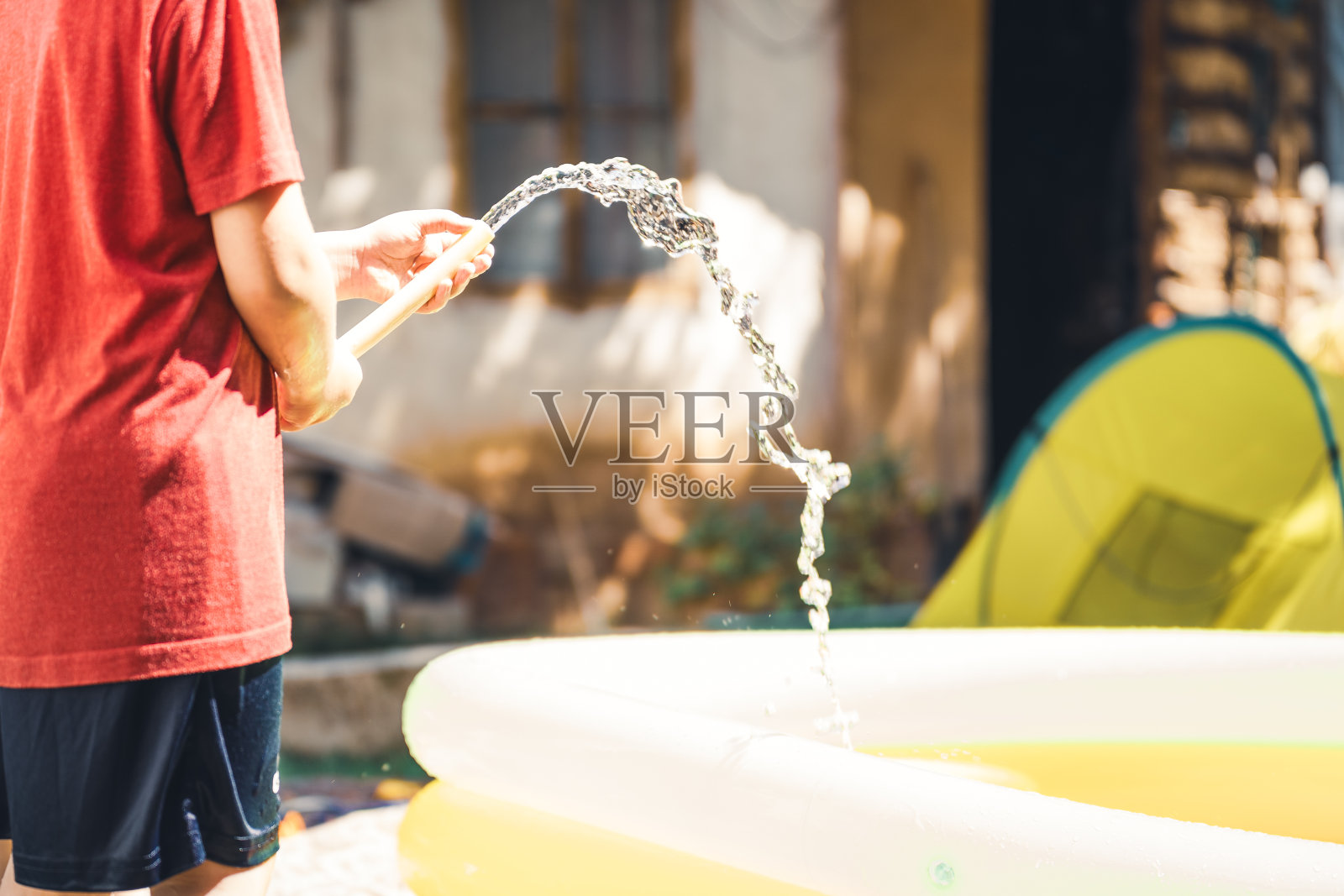 男孩在夏天用水管感觉充气泳池照片摄影图片