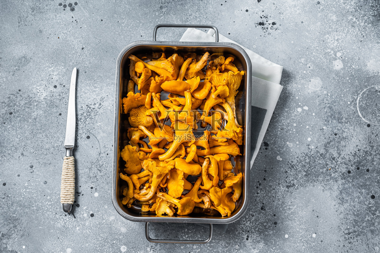 一盘生的野生鸡油菌菇。灰色的背景。俯视图照片摄影图片