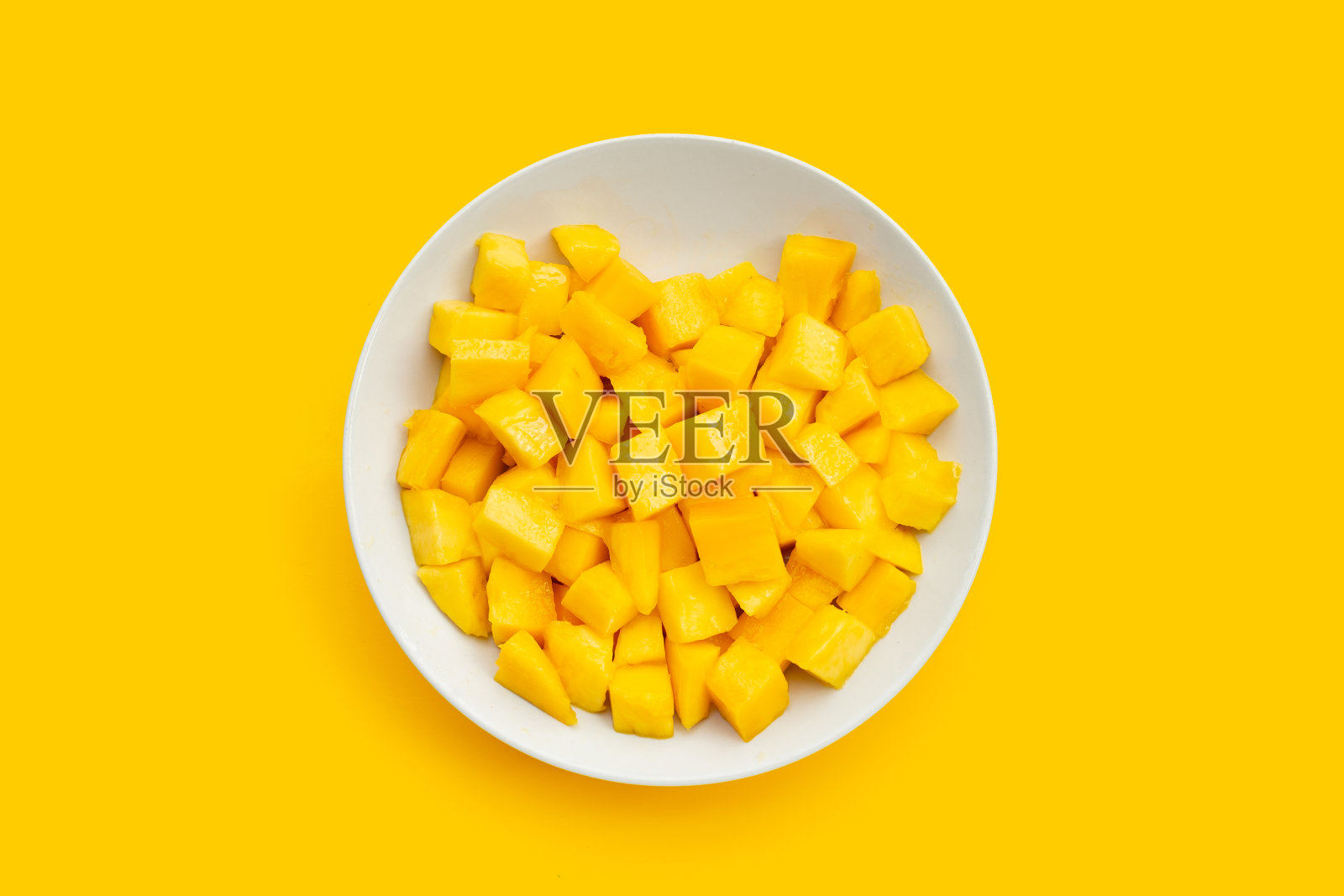 热带水果，芒果方块在白色盘子黄色背景。照片摄影图片