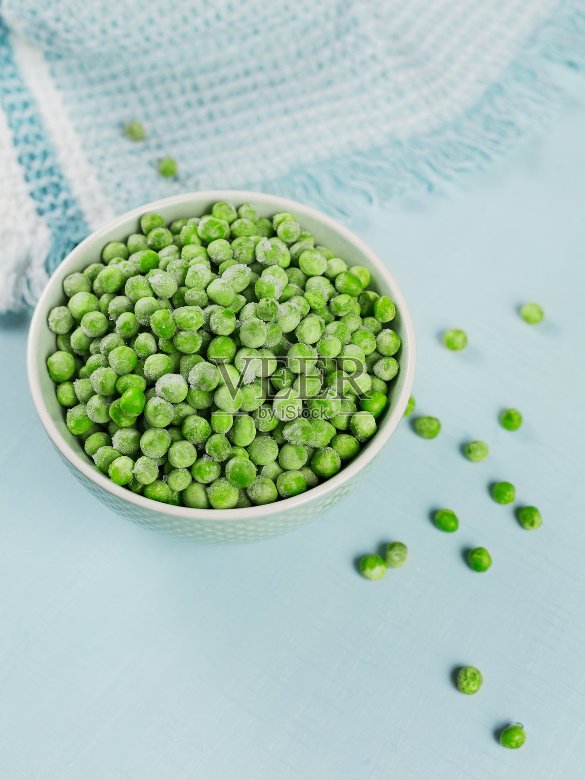 组合与有机冷冻蔬菜在浅蓝色的背景。碗里的绿豌豆。照片摄影图片