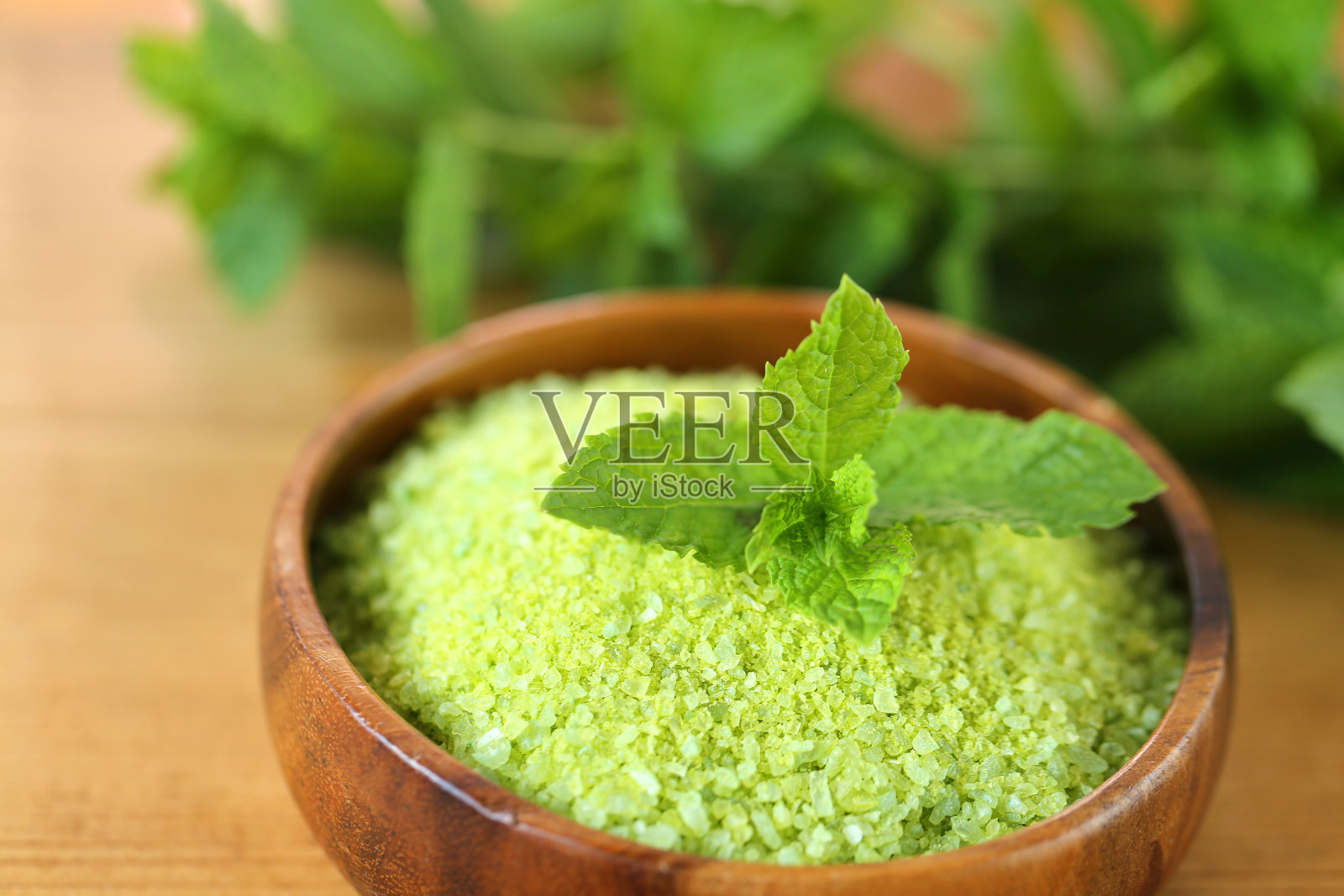 圆木碗里放盐，木桌上放几枝薄荷。盐和薄荷提取物。天然化妆品和芳香疗法的身体与薄荷提取物照片摄影图片