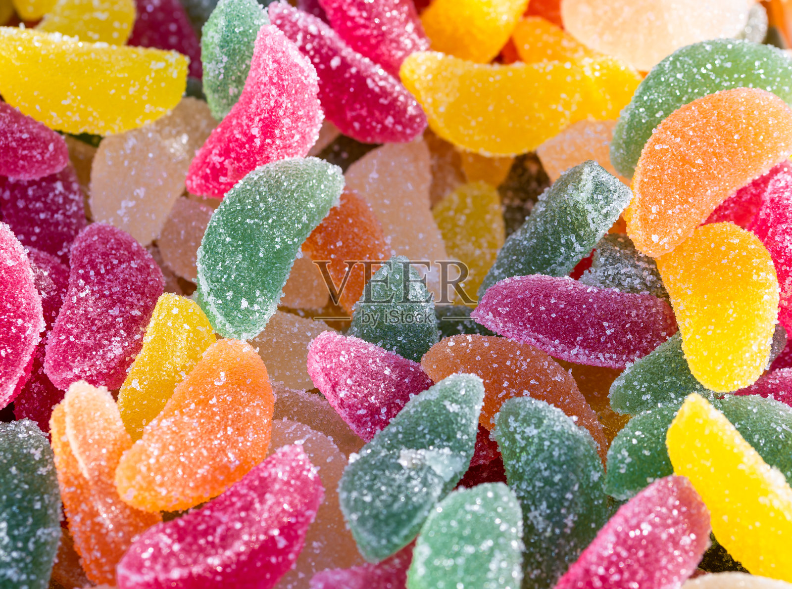 许多五颜六色的果冻豆糖果背景。有糖结晶的软糖块照片摄影图片