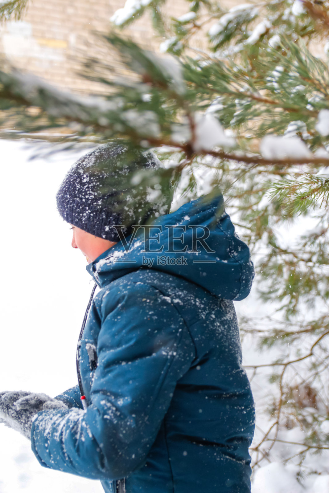 散焦的微笑的孩子男孩在冬天的森林暴风雪。微笑的孩子站在树旁边的雪地背景。积极地花时间在户外。寒霜天气在暴风雪中。特写镜头。的焦点照片摄影图片