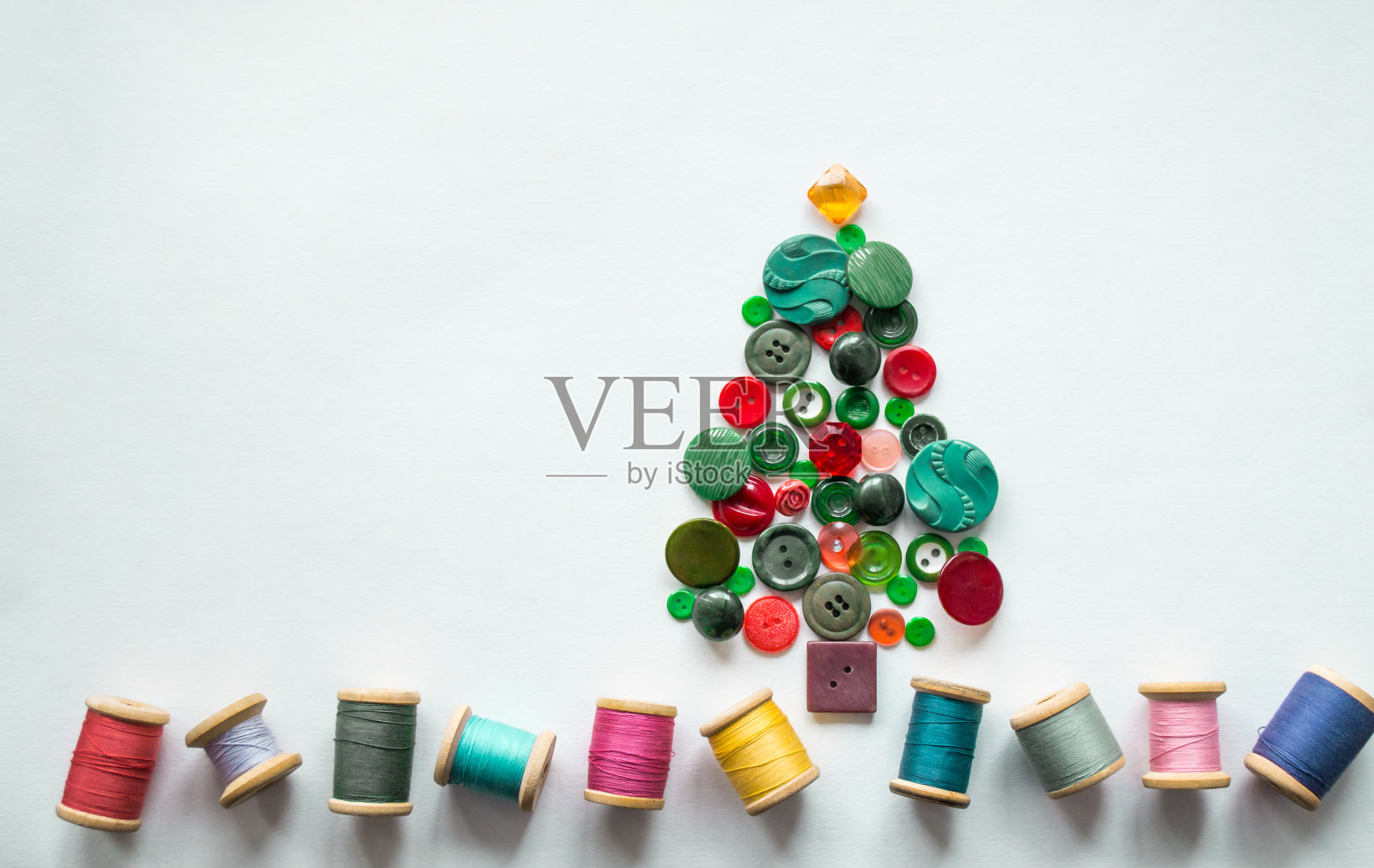 一棵圣诞树，钮扣做成绿色，红色。彩色线与木制线轴。白色背景，复制空间。圣诞创意概念照片摄影图片