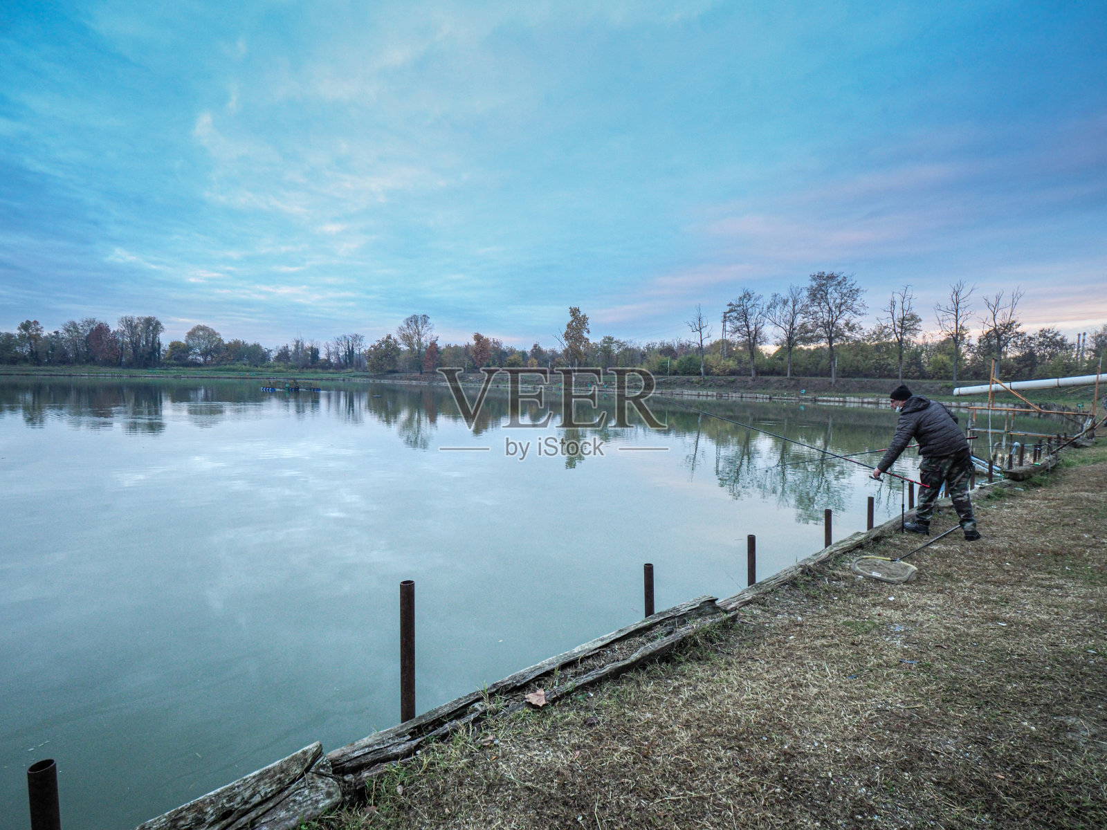 年轻的白人渔夫在湖边钓鱼照片摄影图片