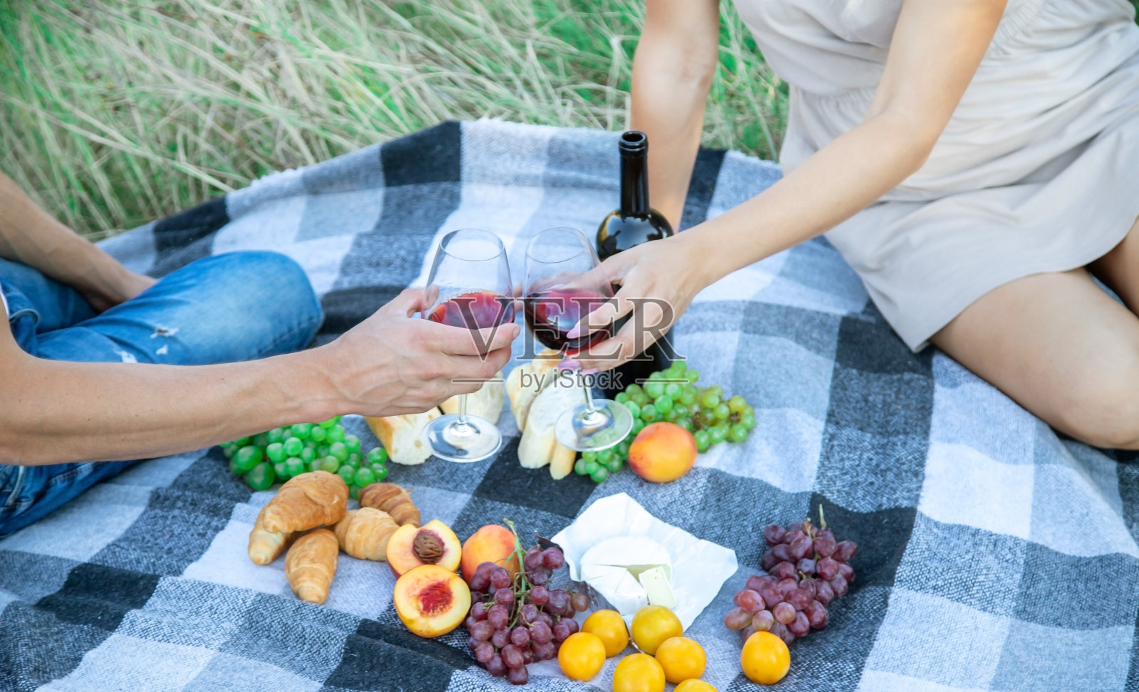 在大自然野餐时，一个女孩和一个男人正捧着盛着酒的酒杯。照片摄影图片